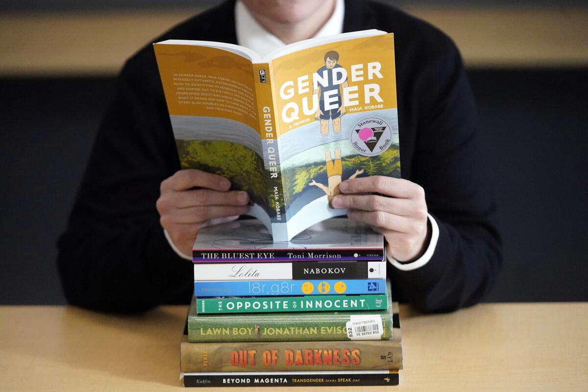 A person holds a book on top of a stack of books