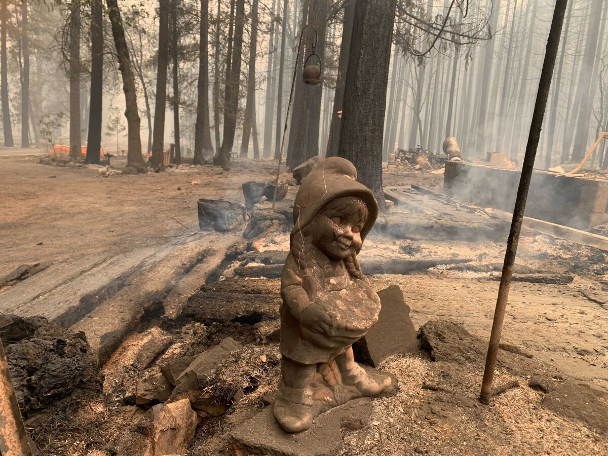 A surviving ceramic statue is seen outside a house that burned along North Arm Road in Plumas County near Taylorsville, Calif., Sunday, Aug. 15, 2021. Thousands of Northern California homes remain threatened by the nation's largest wildfire and officials warn the danger of new blazes erupting across the West is high because of unstable weather. (AP Photo/Eugene Garcia)