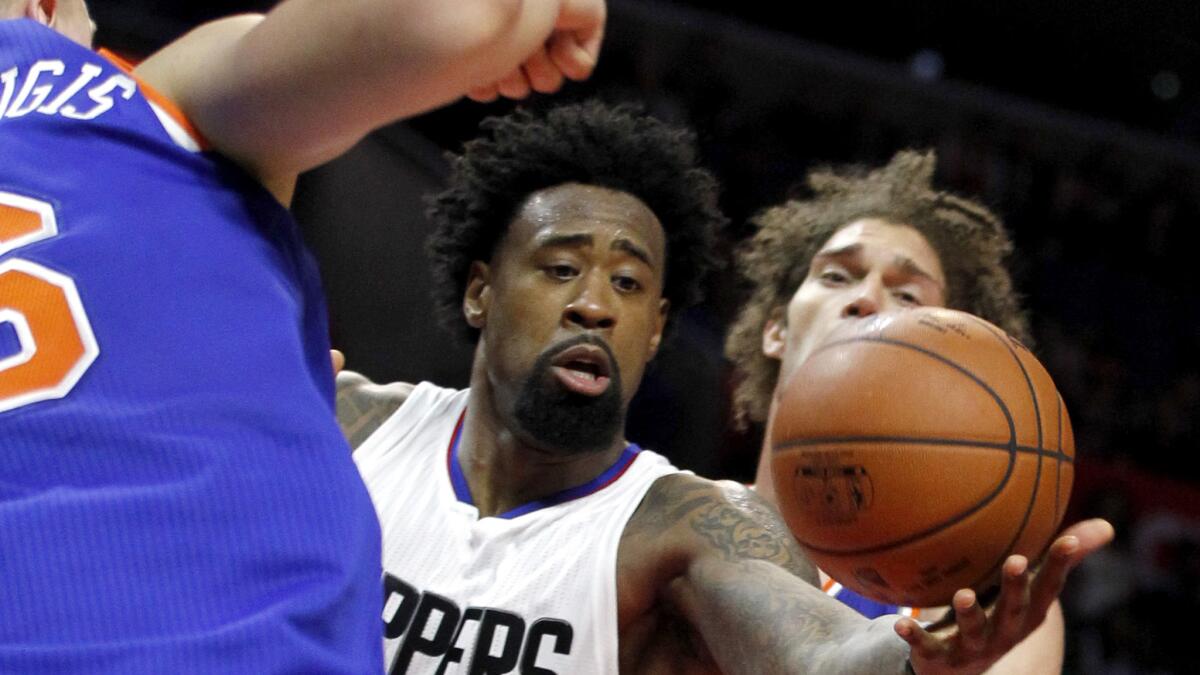 Clippers center DeAndre Jordan reaches for a rebound between Knicks forward Kristaps Porzingis, left, and center Robin Lopez during the second half.