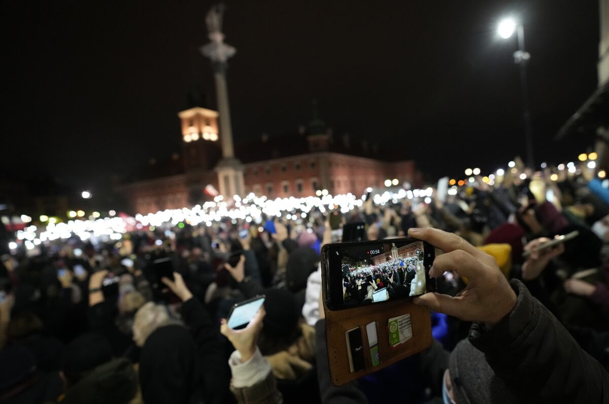 People light up their mobile phone torches in Warsaw, Poland, on Saturday, Nov. 6, 2021, to protest restrictive abortion law that critics say led to a recent death of a woman with troubled pregnancy. The protesters are holding portraits of the woman, 30-year-old Iza, who died in hospital from septic shock. (AP Photo/Czarek Sokolowski)