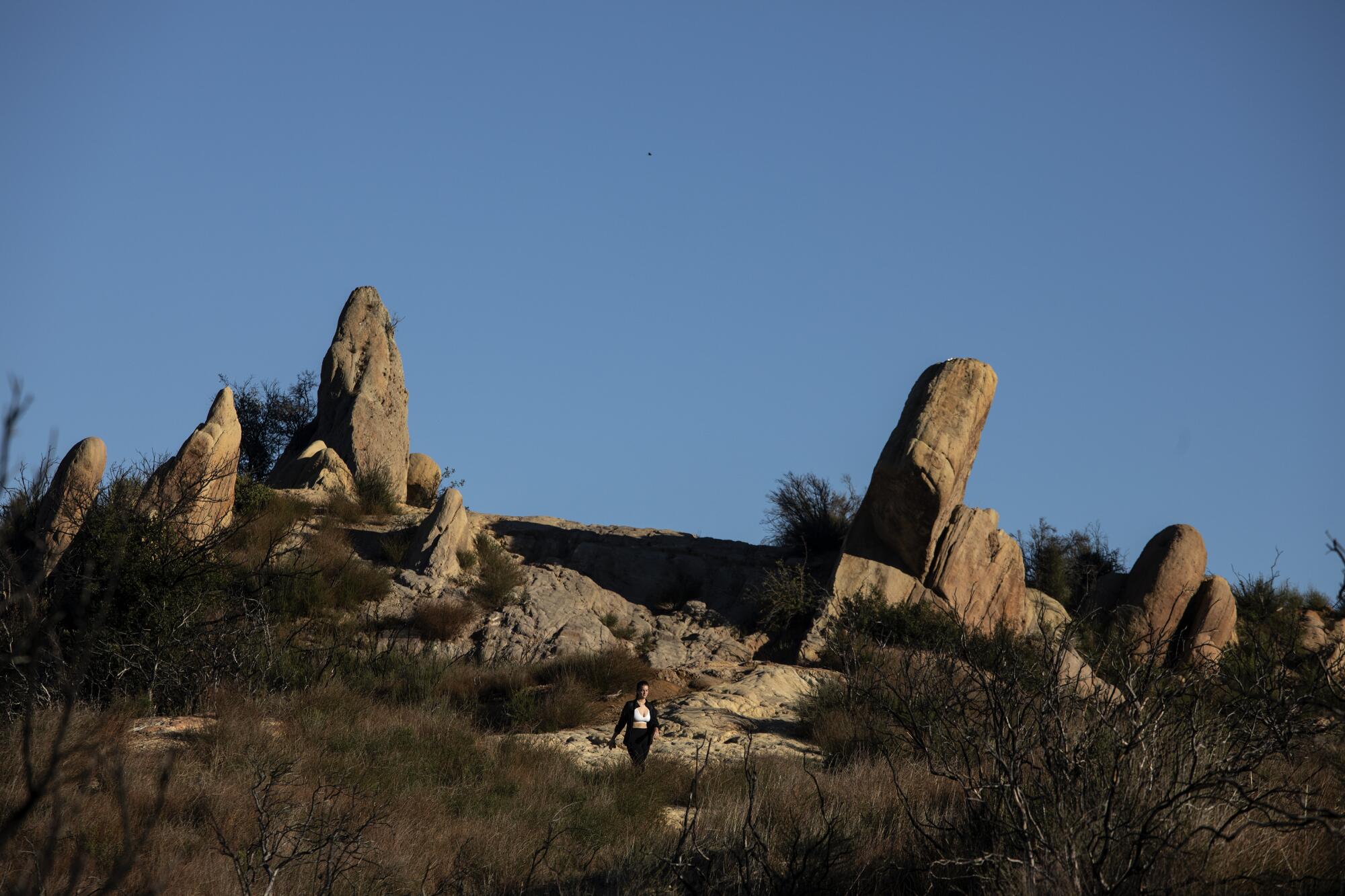 A hiker walks through interesting rock formations along the Backbone Trail in Corral Canyon.