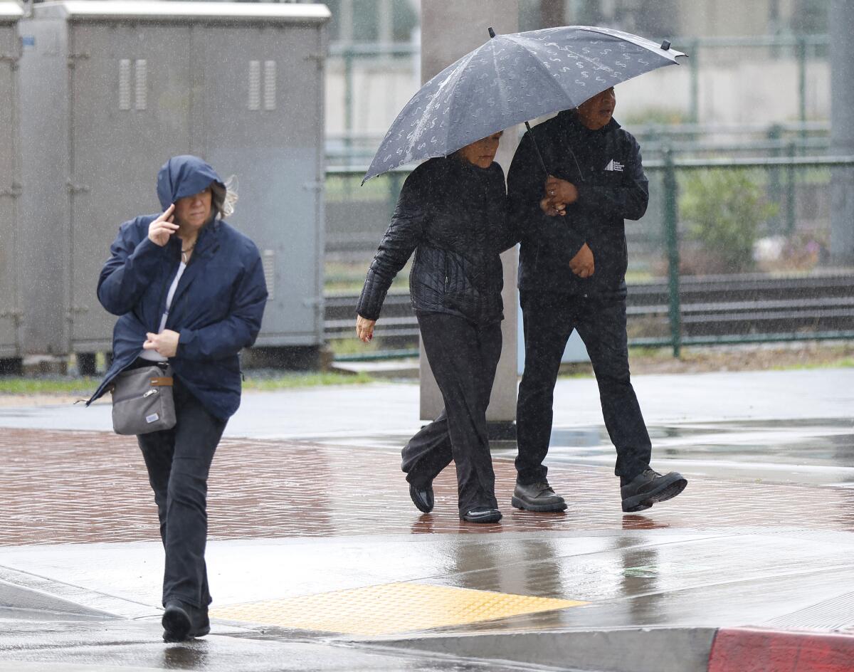 الناس يحتمون تحت المطر في الجادة الخامسة في وسط مدينة سان دييغو.