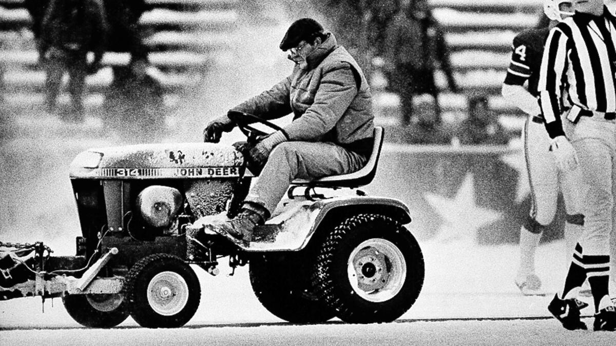 Mark Henderson drives a small tractor fitted with a snow sweeper onto the field at Schaefer Stadium during the third quarter of the New England Patriots' win over the Miami Dolphins on Dec. 12, 1982.