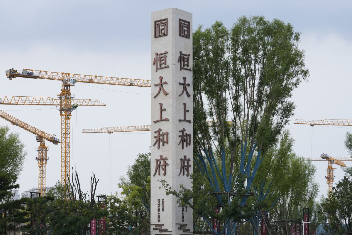 FILE - In this Sept. 15, 2021, file photo, construction cranes stand near the Evergrande's name and logo at its new housing development in Beijing. A mid-size Chinese real estate developer Fantasia Holdings Group failed to make a $205.7 million payment due to bondholders Tuesday, Oct. 5, adding to the industry's financial strain as one of China's biggest developers tries to avoid defaulting on billions of dollars of debt. Investors are worried Evergrande Group might collapse with 2 trillion yuan ($310 billion) of debt. The company has missed at least one payment to bondholders abroad but has yet to be declared in default.(AP Photo/Andy Wong, File)