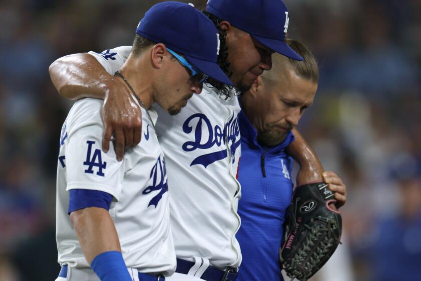 LOS ANGELES, CALIFORNIA - AUGUST 06: Brusdar Graterol #48 of the Los Angeles Dodgers reacts to an injury as he is helped off the field by Enrique Hernández #8 and medical staff during the sixth inning against the Philadelphia Phillies at Dodger Stadium on August 06, 2024 in Los Angeles, California. (Photo by Harry How/Getty Images)