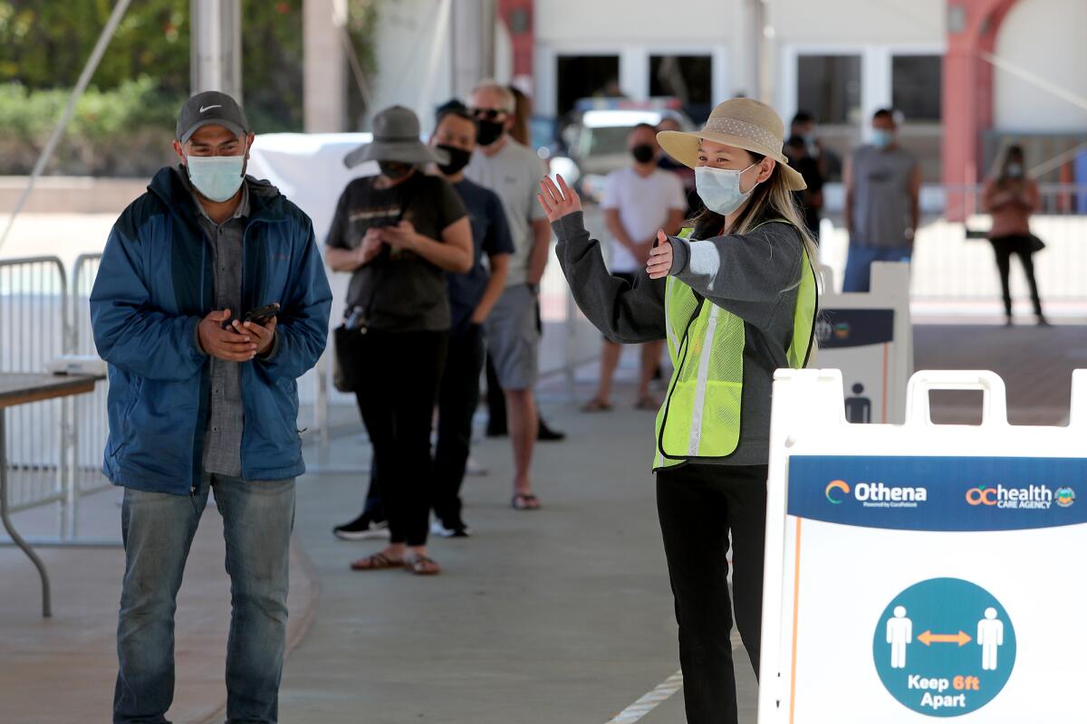 A worker directs appointment holders at a COVID-19 vaccination super POD site at the Orange County fairgrounds in Costa Mesa.