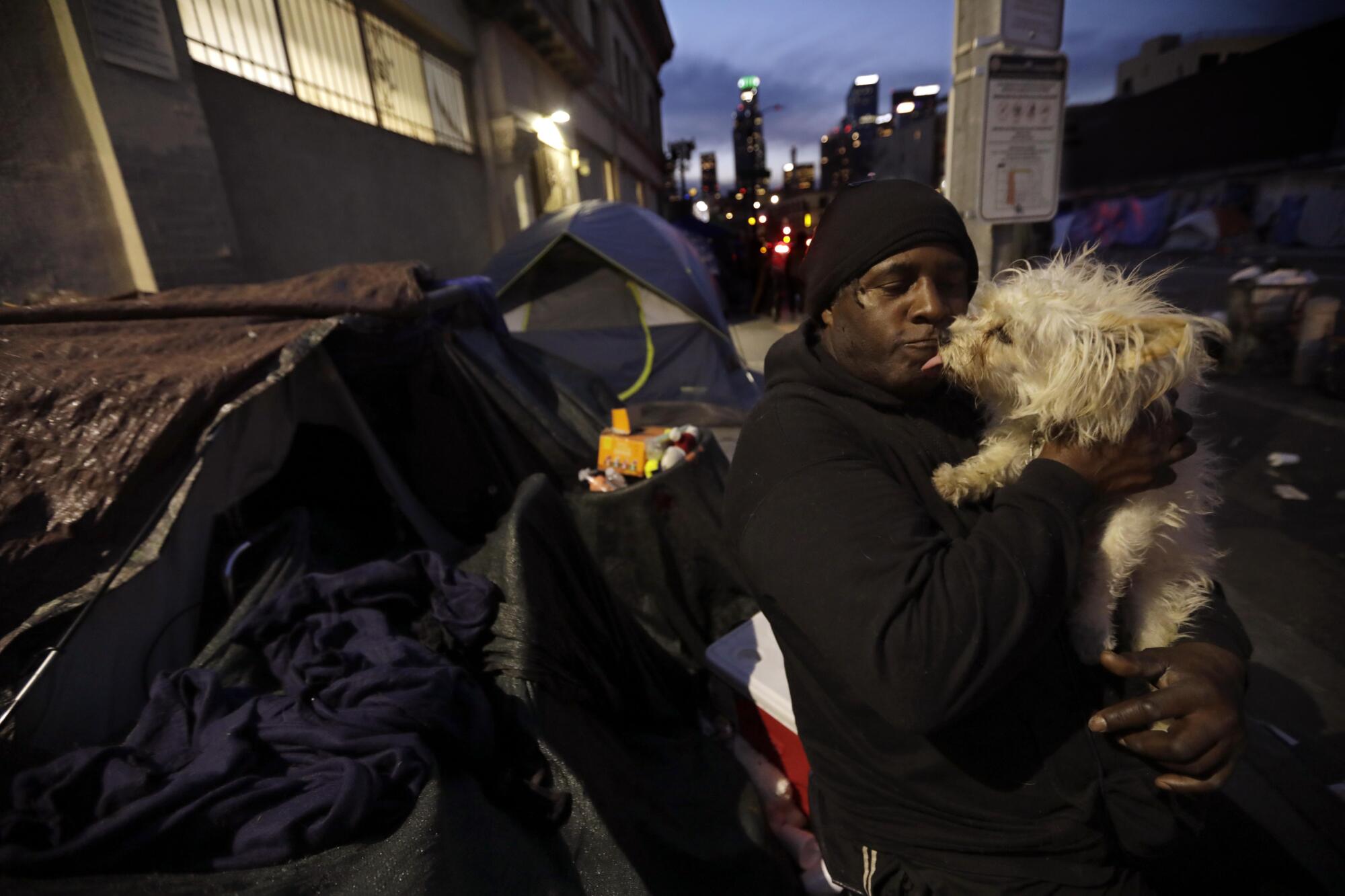 Gregory Gibson holds his dog in front of his tent in skid row 