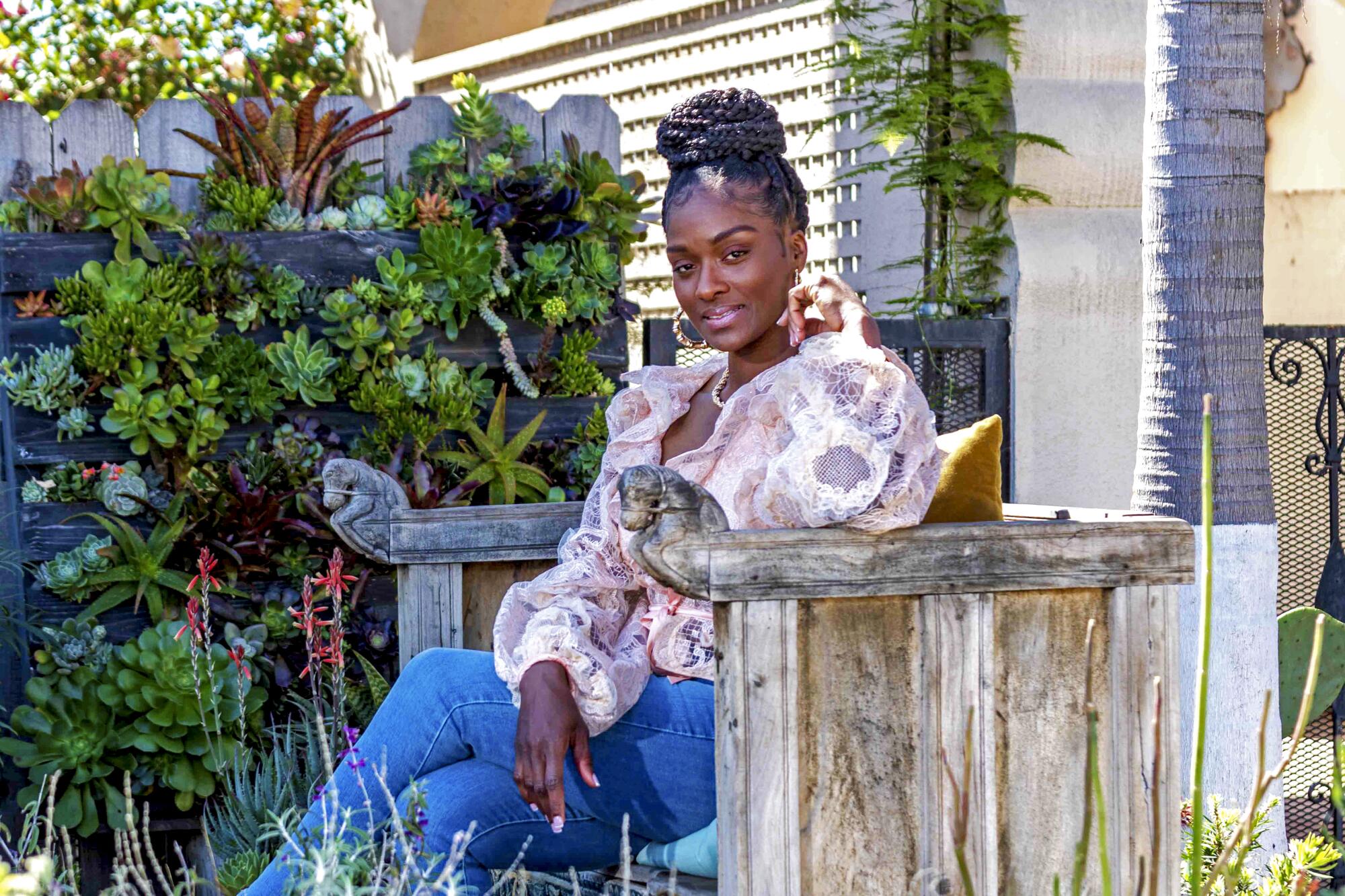 Brandy Williams sits on a bench surrounded by succulents 