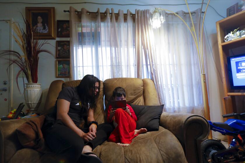 Francisco Martinez, 22 spends the morning with his youngest brother, Cristian Gomez, 4 who is enjoying a video game on his hand held device. The brothers live with their mother and two other brothers in Barrio Logan.