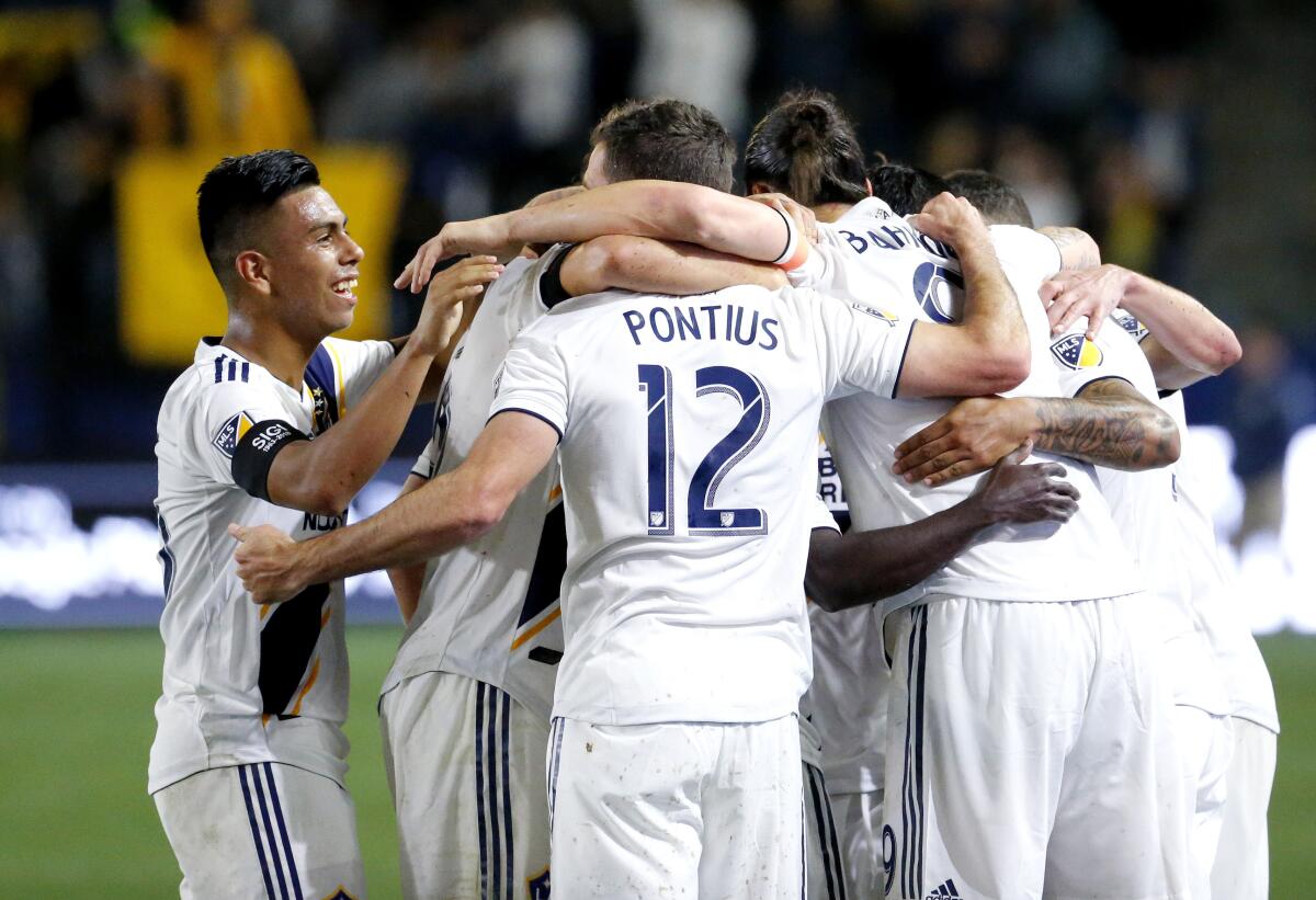 In this Saturday, March 2, 2019 photo, LA Galaxy midfielder Efrain Alvarez, left, joins teammates celebrating their their goal against Sporting Kansas City during an MLS soccer match in Carson, Calif. U.S. coach Gregg Berhalter is monitoring Efrain Alvarez, the 16-year-old midfielder who had an assist in his LA Galaxy debut last weekend and is eligible to play for both the Americans and Mexico.(AP Photo/Ringo H.W. Chiu)