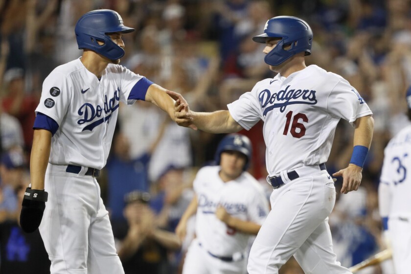 Los Angeles Dodgers' Corey Seager, left, and Will Smith celebrate after scoring on a double by Chris Taylor during the eighth inning of a baseball game against the Los Angeles Angels in Los Angeles, Saturday, Aug. 7, 2021. (AP Photo/Alex Gallardo)