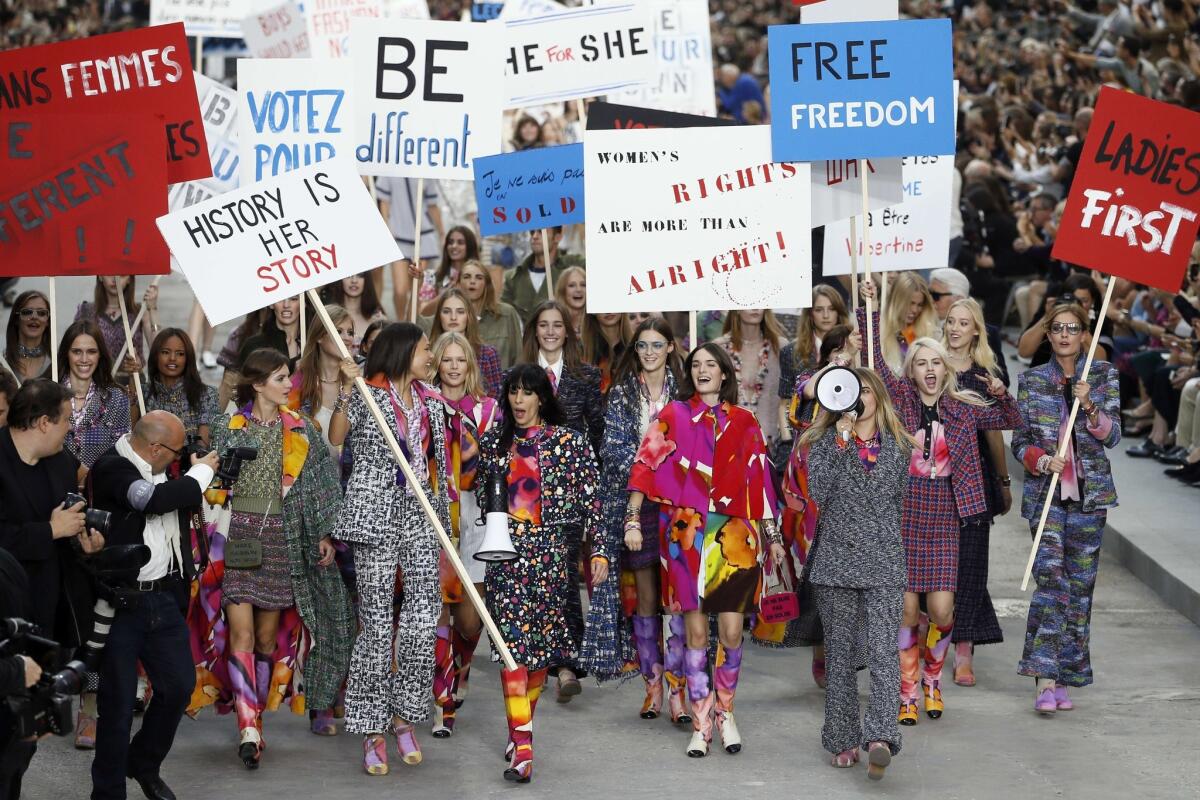 Models carry signs with slogans such as, "History is her story" and "Women's rights are more than alright!" at Chanel's Paris Fashion Week show on Sept 30.