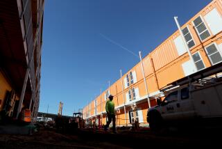 LOS ANGELES, CA. - DEC. 30, 2020. L.A. County contractors are rushing to complete a 232-unit homeless housing project in downtown Los Angeles. Authorities said the project will be a milestone for speed and economy. The prefab units, built with CARES funds, are largely made of shipping containers. They will start out as shelters and transition into permanent housing. The project began in September and will be completed in January at a cost of just over $200,000 per unit. (Luis Sinco/Los Angeles Times)