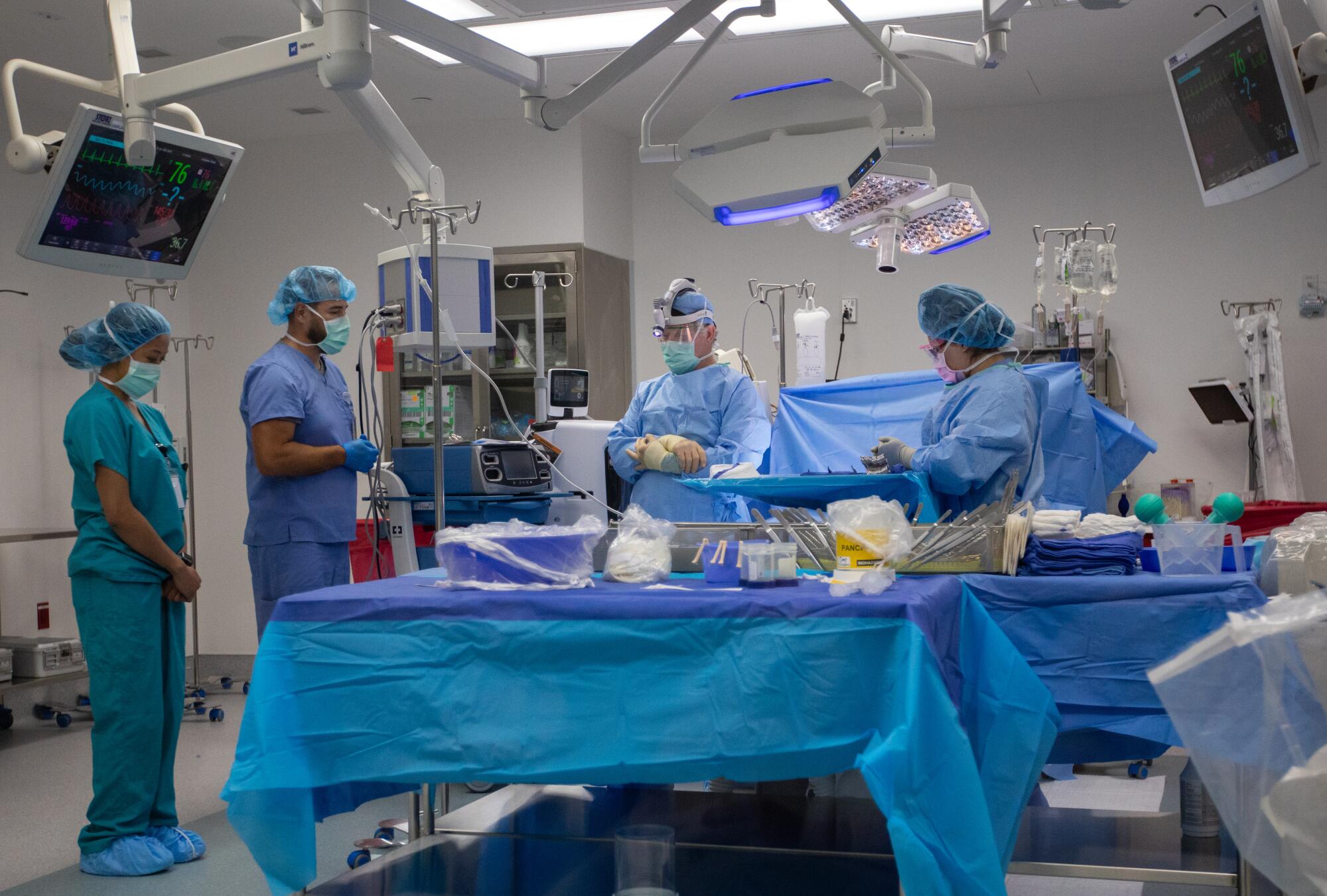 A surgical team stands around a covered operating table in an operating room 