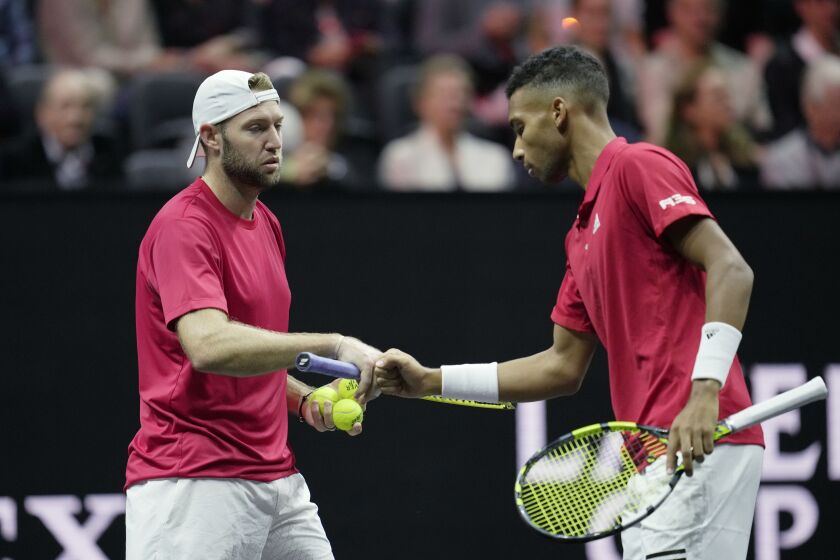 Team World's Jack Sock, left, and Felix Auger-Aliassime react during a match against Team Europe's Andy Murray, left, talks to Matteo Berrettini on final day of the Laver Cup tennis tournament at the O2 in London, Sunday, Sept. 25, 2022. (AP Photo/Kin Cheung)