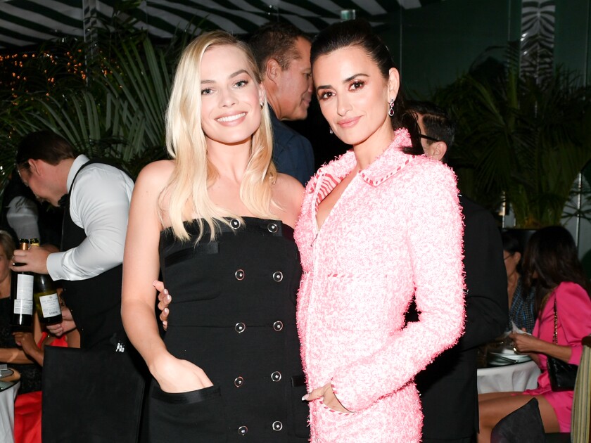 Margot Robbie wraps an arm around Penélope Cruz.