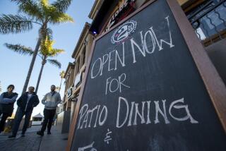 HUNTINGTON BEACH, CA - January 26: Pedestrians walk by a sign advertising patio dining at 2nd Floor Huntington Beach on Main Street Tuesday, Jan, 26, 2021. Although outdoor dining across the state is not suppose to resume until Friday, many OC restaurants have been open. The stay at home order has been lifted by California PublicHealth for all regions statewide. Orange County will operate in the most-restrictive "purple" reopening tier, which means restaurants may resume outdoor dining, while barbers, nail and hair salons can reopen in a limited capacity. (Allen J. Schaben / Los Angeles Times)