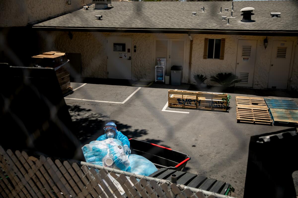 A worker throws out of large bags of used protective equipment at the Reo Vista Healthcare Center.