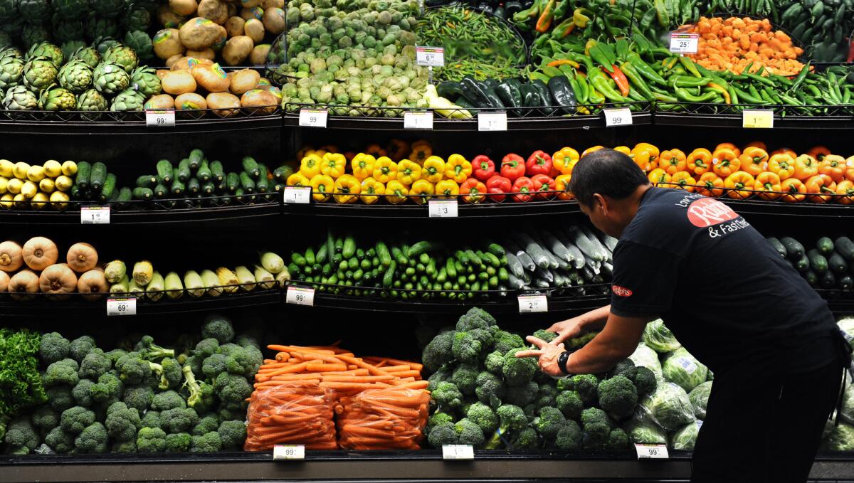 Produce clerk Frank Duenas arranges vegetables at the Ralph's grocery store in downtown L.A. Food prices are a key factor in the federal government's inflation calculations.