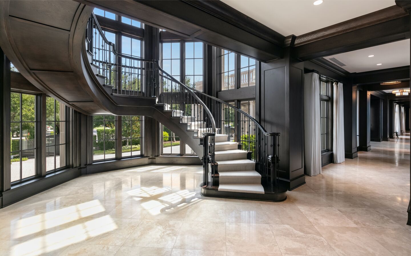 A winding, floating staircase backed by a wall of windows.