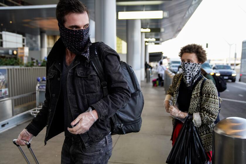 LOS ANGELES, CALIF. - MARCH 04: Travelers, wearing masks as a precaution to protect against the spread of the COVID-19, coronavirus, make their way through the Tom Bradley International Terminal at Los Angeles International Airport on Wednesday, March 4, 2020 in Los Angeles, Calif. In an email obtained by NBC News, the Department of Homeland Security says that Aamedical professional who conducted passenger screenings at LAXtested positive for the coronavirus late Tuesday night. (Kent Nishimura / Los Angeles Times)