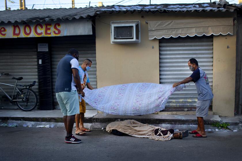 Rio de Janeiro, Brazil : Neighbors cover the the body of Luiz Carlos Da Rocha, 36, with a sheet, as he lies on a street where he dropped dead at the Alemao Complex slum of Rio de Janeiro, Brazil, Tuesday, April 28, 2020. After more than 12 hours on the street the body of Da Rocha, who the family said suffered from epilepsy, had not been picked up by authorities. Military police said that due the new coronavirus pandemic, they only can remove corpses in cases of violent death. (AP Photo/Silvia Izquierdo)