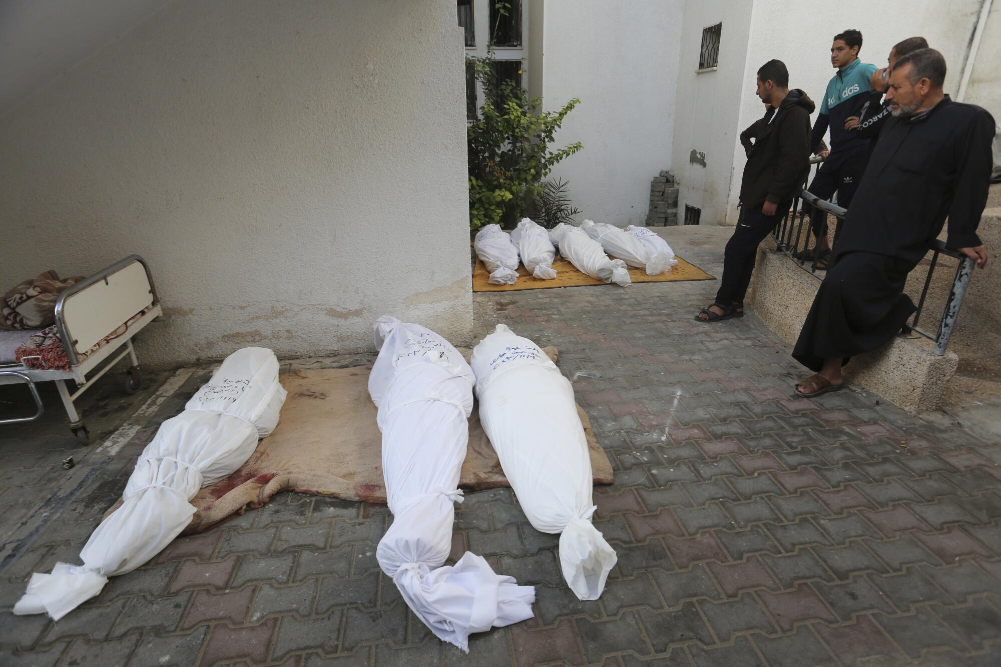 People standing by enshrouded bodies of family killed in Israeli bombardment of Gaza