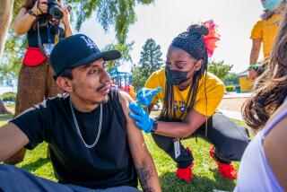 Asia Hartford, LVN, right, administers a covid vaccine to Luis Fernandez