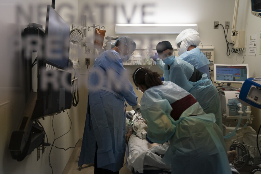 An EMT looks at a monitor while performing chest compression on a patient who tested positive for coronavirus.