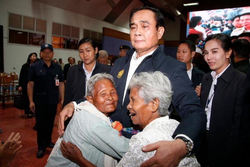 In this March 13, 2019, photo, elderly locals hug Prime Minister Prayuth Chan-ocha and candidate for the same position, as he attends a government-sponsored event in Nakhon Ratchasima, Thailand. Prayuth has been nominated by a pro-army political party to become prime minister again after the March 24 general election. (AP Photo/Sakchai Lalit)