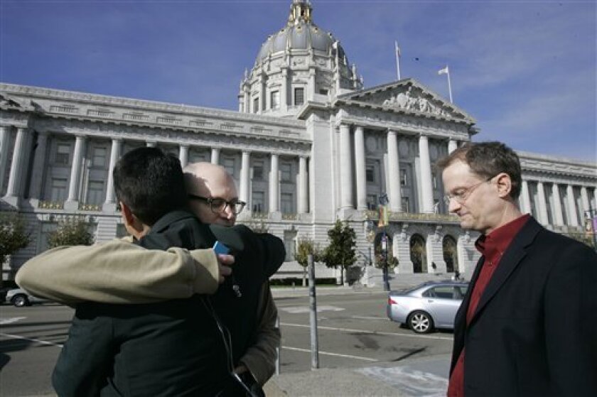 Gay rights activist Stuart Gaffney, left, gets a hug from friend, Patrick Connors, center, as Gaffney's partner John Lewis, right, looks on outside of City Hall, where Gaffney and Lewis married this past summer, in San Francisco, Wednesday, Nov. 5, 2008. In an election otherwise full of liberal triumphs, the gay rights movement suffered a stunning defeat as California voters approved a ban on same-sex marriages that overrides a recent court decision legalizing them. (AP Photo/Marcio Jose Sanchez)