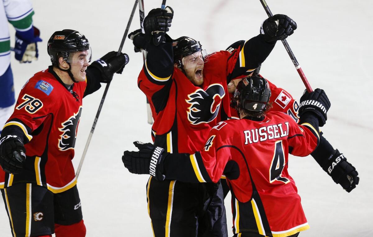 Calgary's Matt Stajan, center, celebrates his eventual game-winning goal with teammates Michael Ferland, left, Kris Russell and David Jones against the Vancouver Canucks on Saturday.