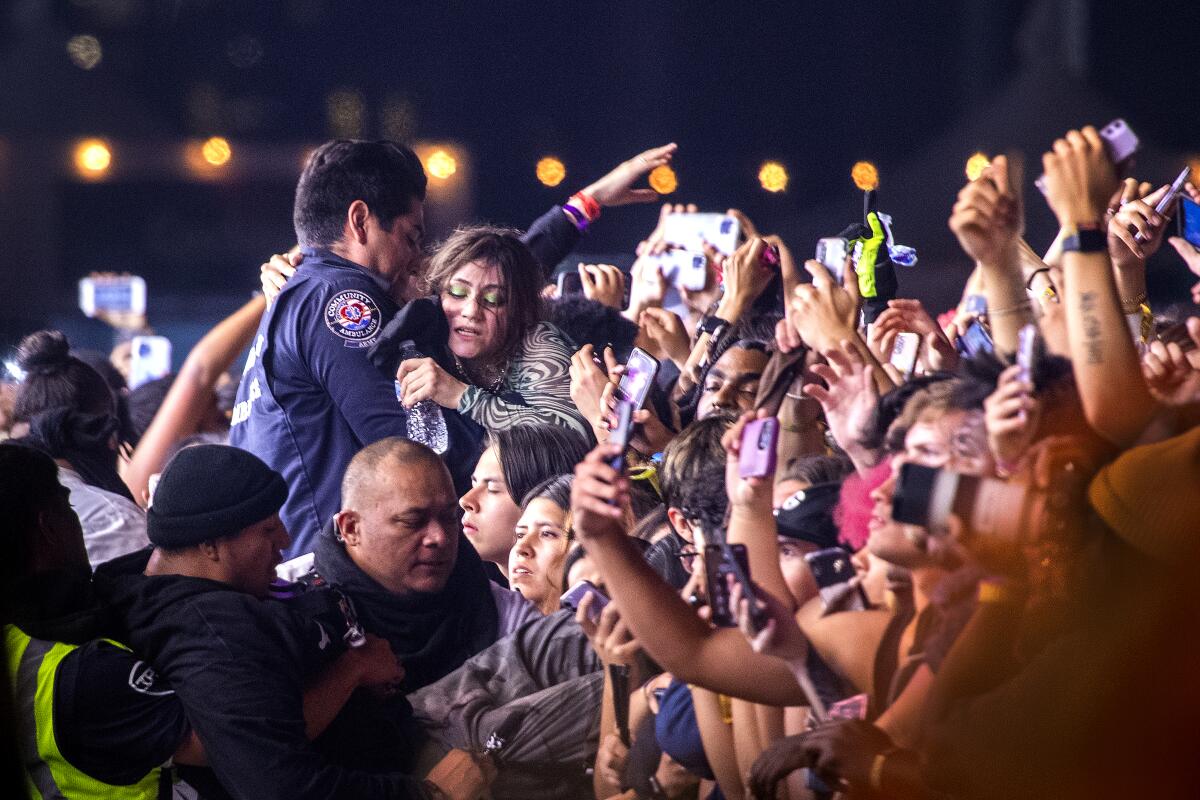 An EMT and security officers pull fans in distress out of the crowd