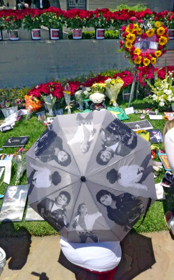 A Michael Jackson well-wisher with a personalized Michael Jackson umbrella, reads some the cards left at Forest Lawn Memorial Park in Glendale.