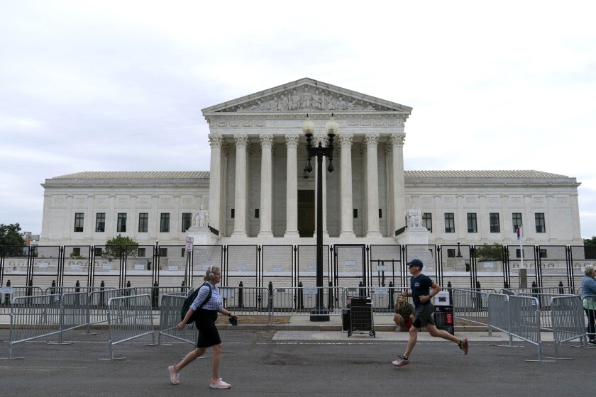 A jogger and a woman with backpack pass the U.S. Supreme Court