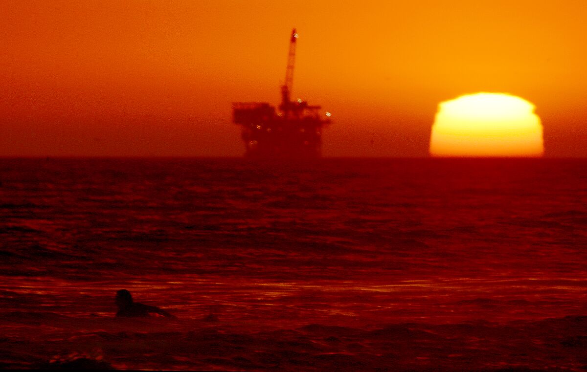 HUNTINGTON BEACH, CALIF. - SEP. 5, 2022. A surfer paddles out as the sun sets at Huntington Beach