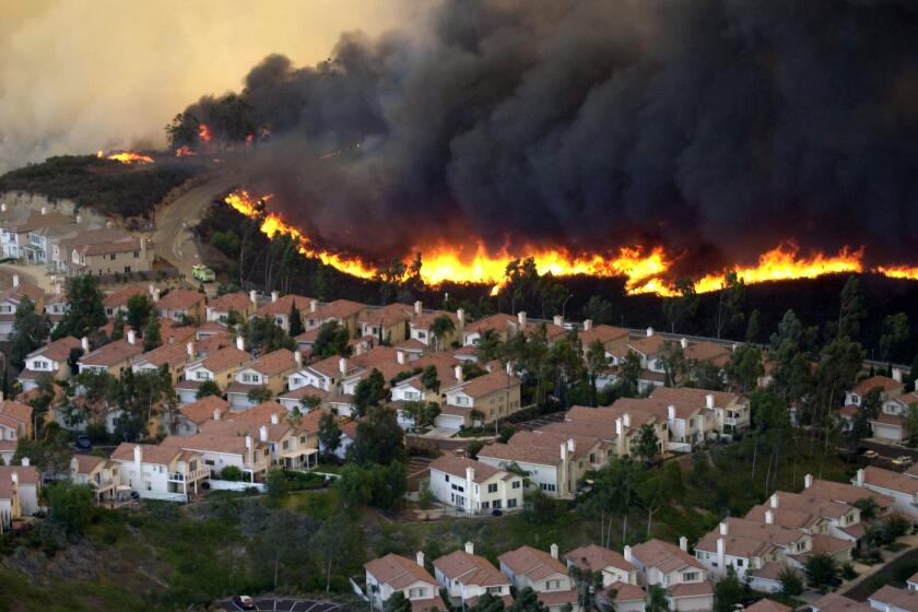 Fire burns towards houses in Scripps Ranch along Pomerado Road in San Diego on Oct. 26, 2003.