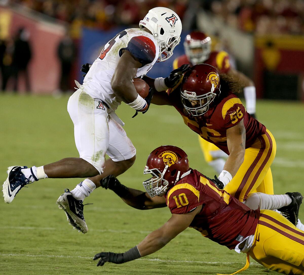 Trojan defenders Anthony Sarao, No. 56, and Hayes Pullard, No. 10, close in on Arizona running back Ka'Deem Carey during a game on Oct. 10, 2013.