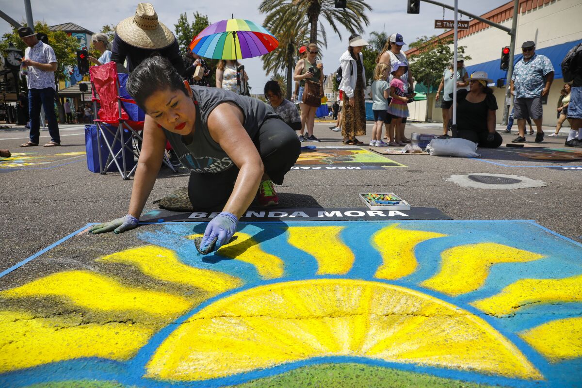 Brenda Mora, a Chula Vista native, works on a colorful chalk drawing depicting a lemon slice.