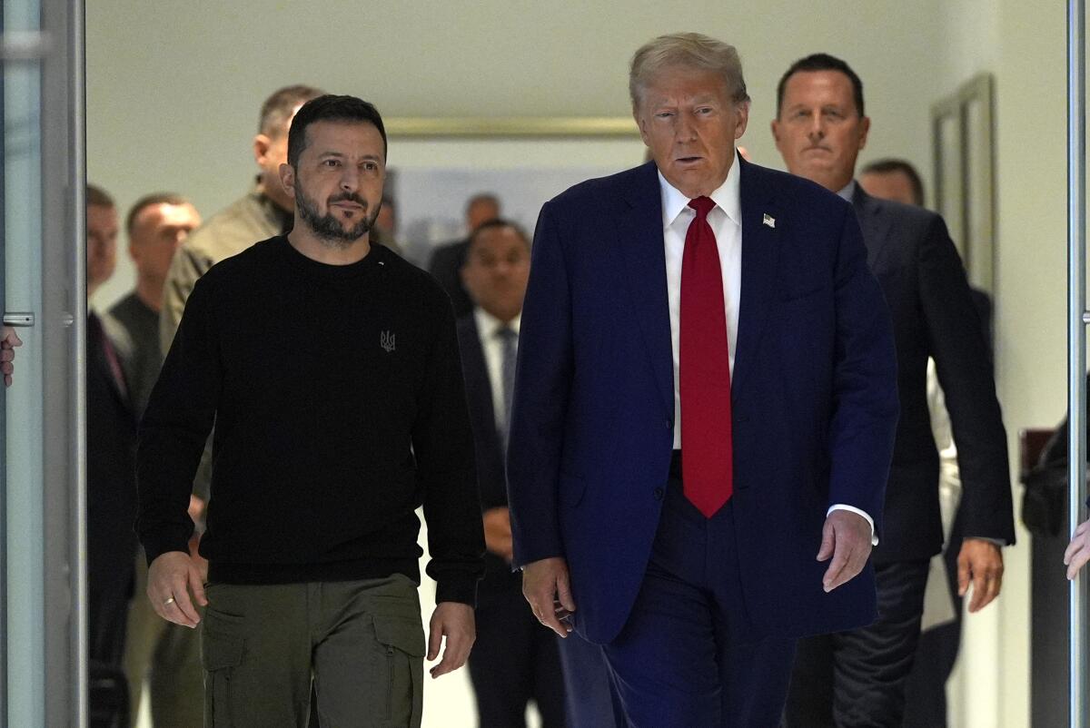 Former President Trump walks with Ukrainian President Volodymyr Zelensky in a hallway.