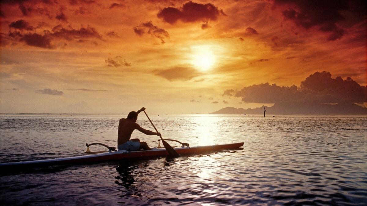 A native man kayaks as the sun sets in Papeete, Tahiti. Air Tahiti Nui is offering a bargain round-trip fare of $999 from LAX for fall and winter travel.