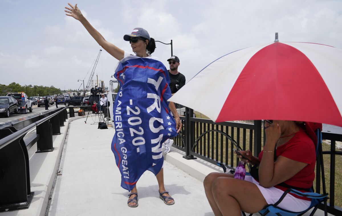 A Donald Trump supporter stands on a bridge outside the entrance to former President Trump's Mar-a-Lago estate Tuesday.