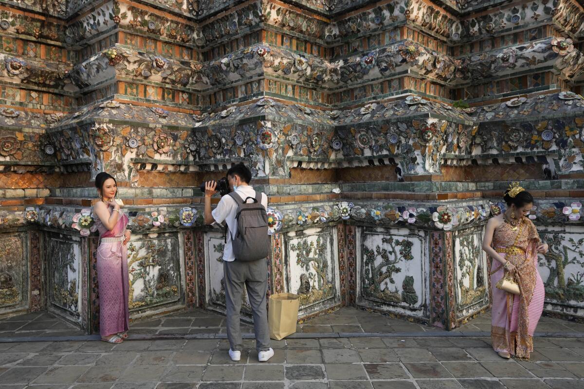 ARCHIVO - Una turista china con un vestido tradicional tailandés posa para una foto en Wat Arun, 