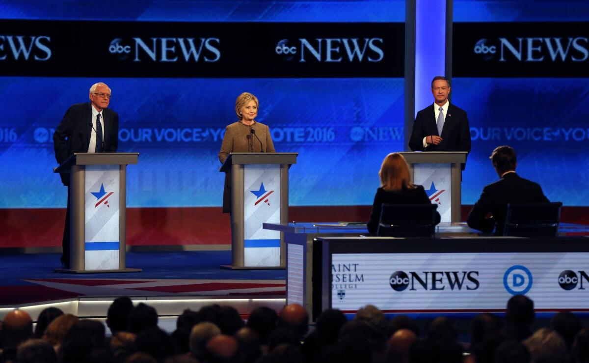 Bernie Sanders, left, Hillary Clinton, center, and Martin O’Malley take the stage for a Democratic presidential primary debate Saturday, Dec. 19, 2015, at Saint Anselm College in Manchester, N.H. Seated at the table are debate moderators Martha Raddatz, left, and David Muir, of ABC News. (AP Photo/Jim Cole)