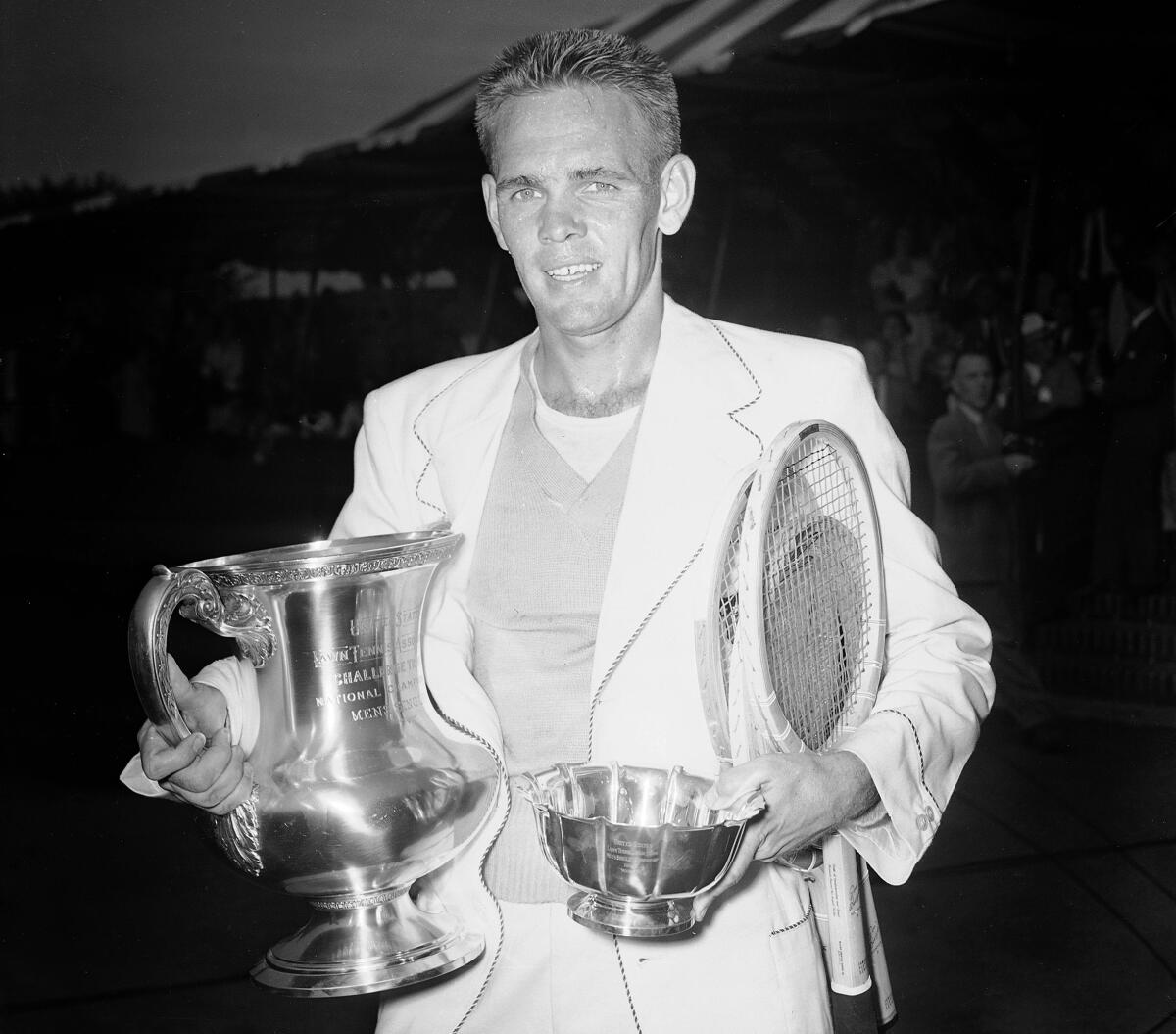 Jack Kramer stands at the West Side Tennis Club in Forest Hills, New York, with the trophies.