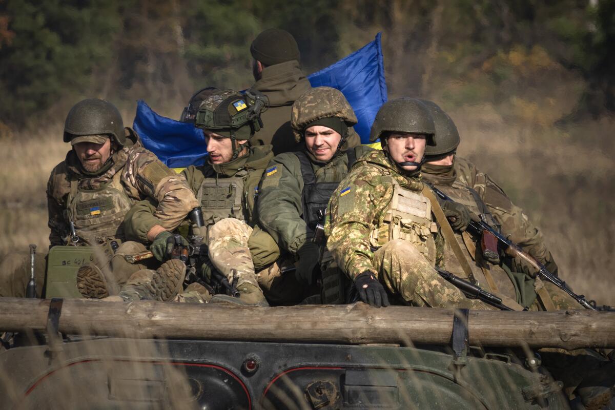 Ukrainian soldiers ride atop a military vehicle during training