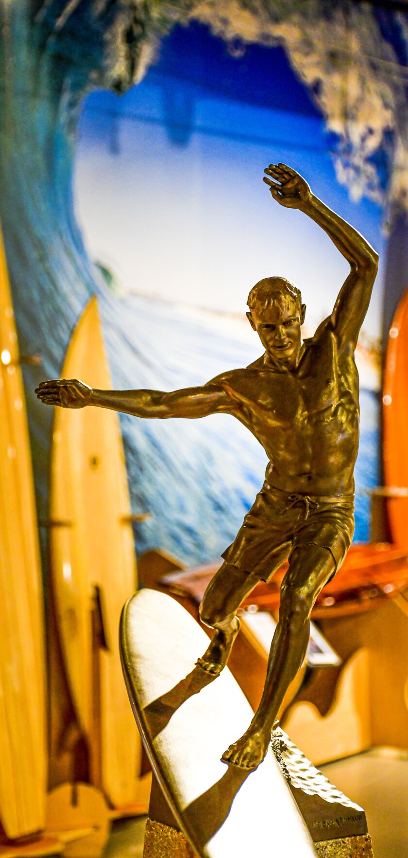 A surfing trophy with surfboards on display in the background.