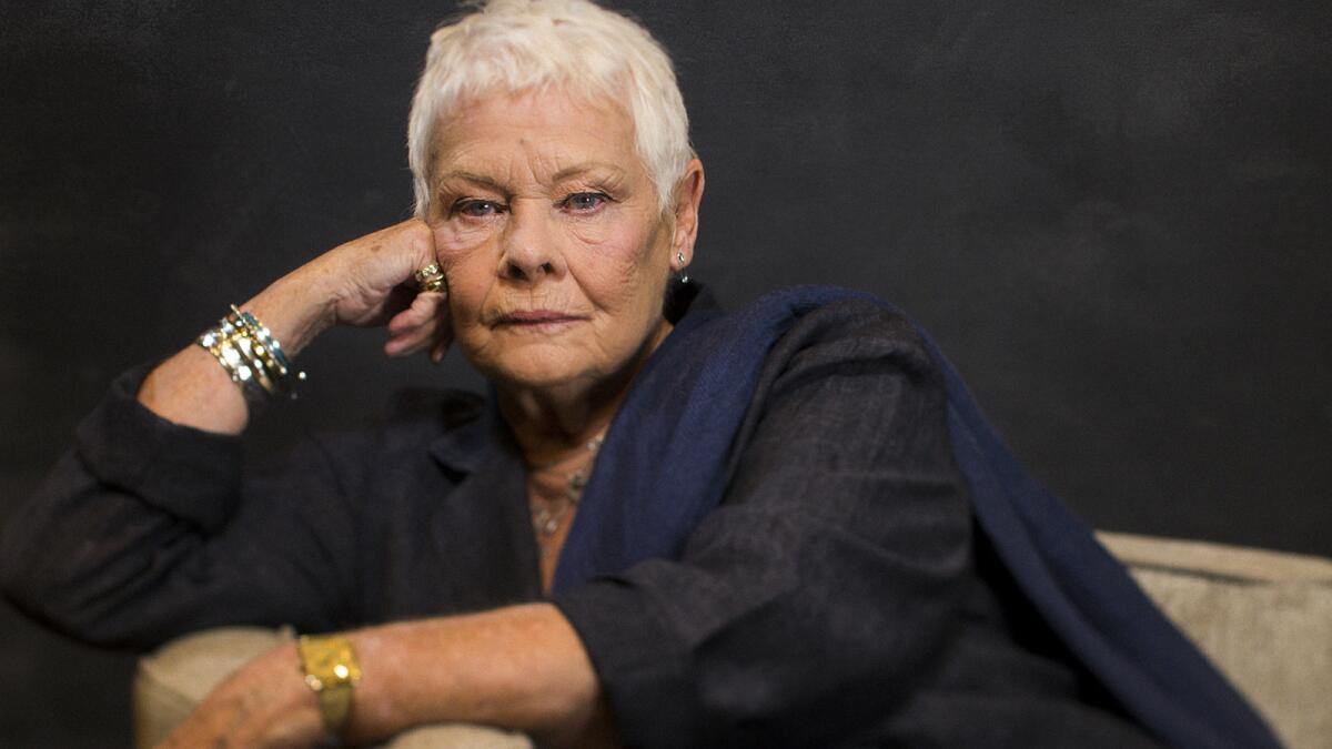 A woman with cropped white hair leans her face on her closed hand while seated