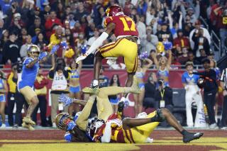 UCLA's Kwazi Gilmer holds the ball under pressure from USC's Marcelles Williams as Decarlos Nicholson leaps over them