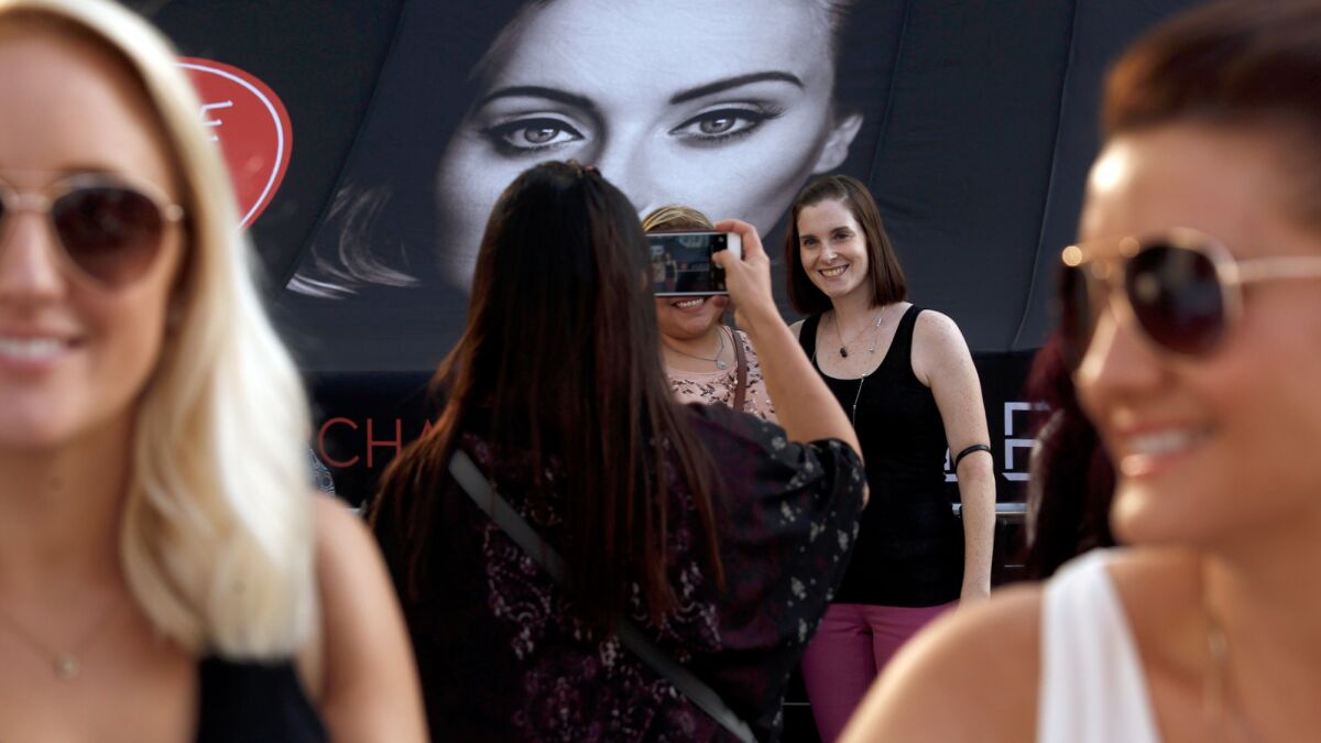 Fans of Adele have their picture taken next to a photo of the singer at the first of her eight night sold out shows at Staples Center.
